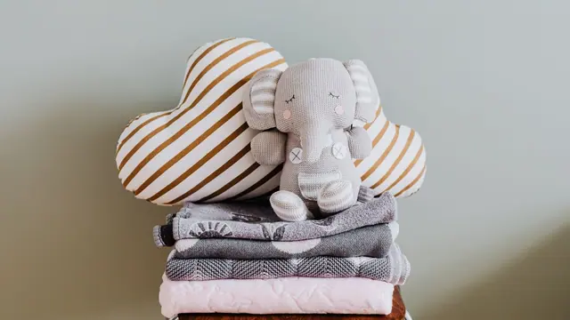 An elephant toy on blankets with a striped cushion on a chair