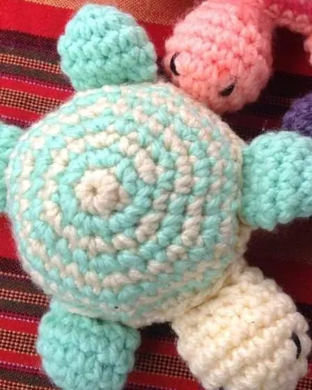 A crocheted turtle with a mint and cream shell