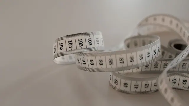 White sewing tape measure coiled on a grey surface