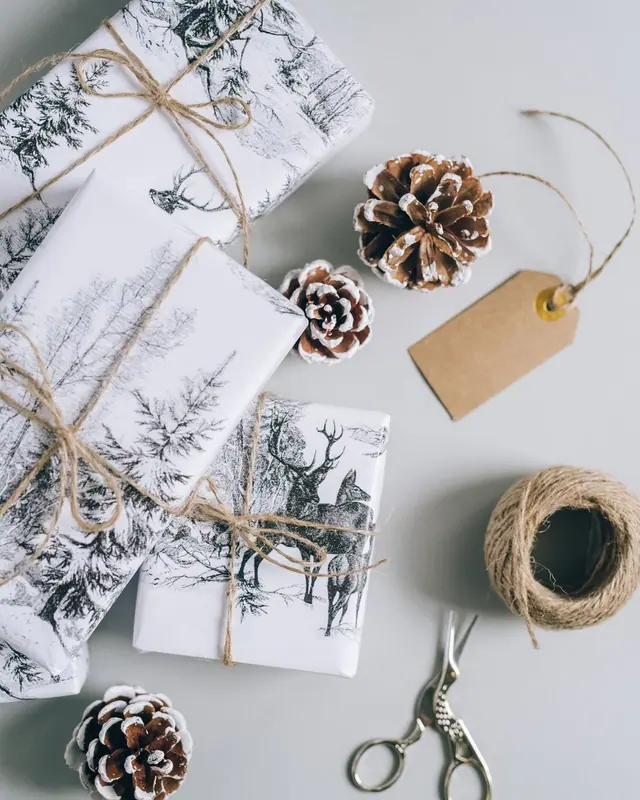 Overhead view of kraft gifts with twine, pine cones and a tag