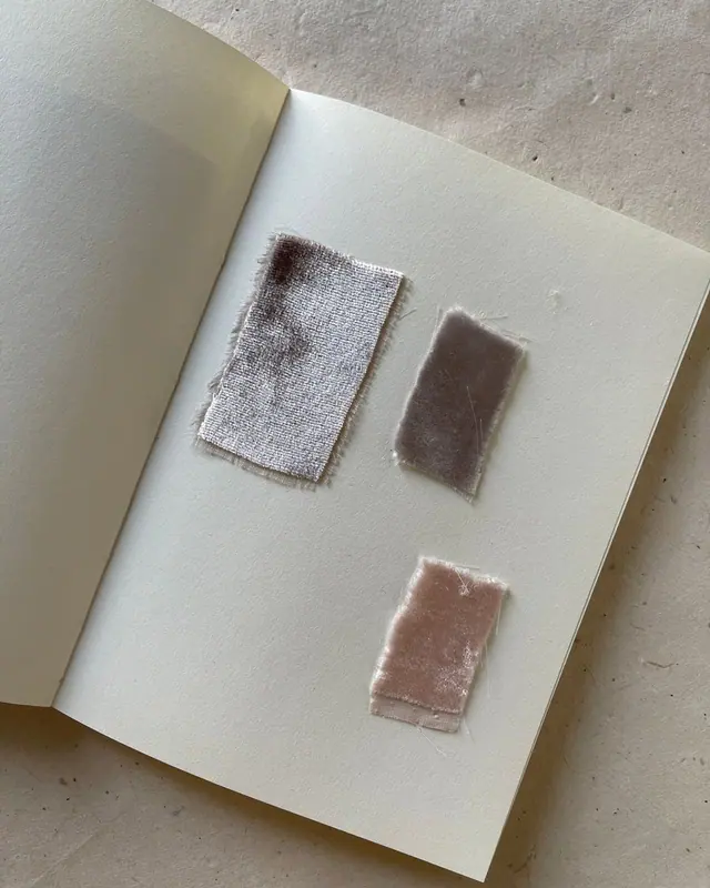 Fabric samples glued into a cream notebook