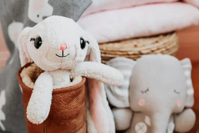 A plush bunny in a brown boot beside a small elephant toy
