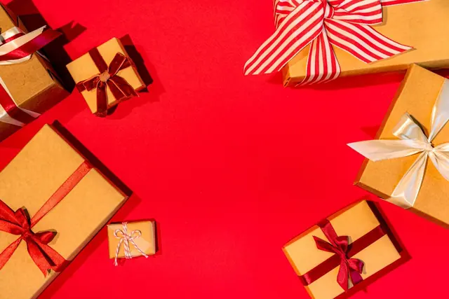 Overhead view of kraft gift boxes with ribbons on a red surface