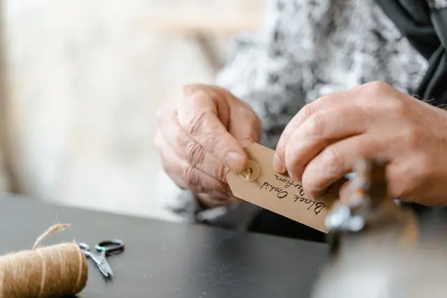 Hands attaching a handwritten tag to a gift with jute string