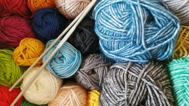Balls of coloured yarn with wooden crochet hooks laid on top