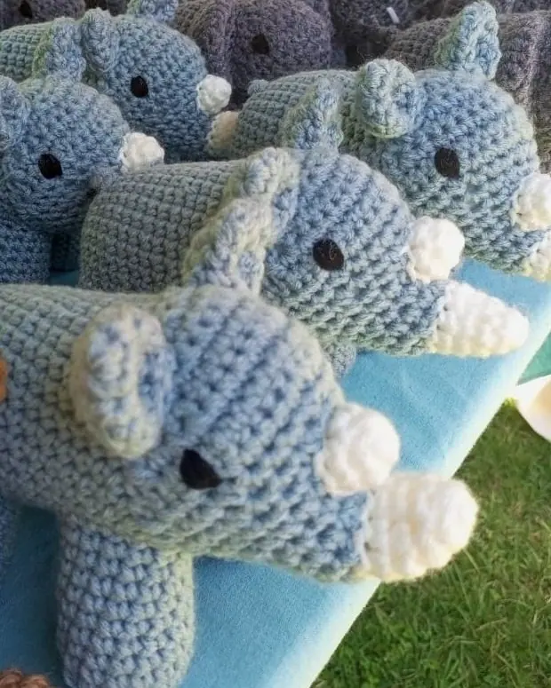 Light blue crocheted rhinos with cream horns on a table