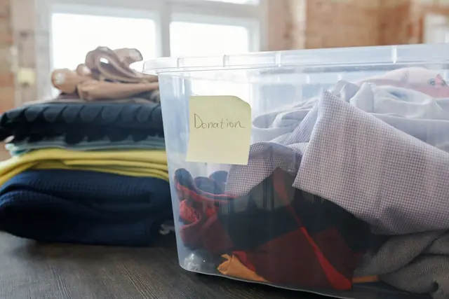A plastic box of folded clothes marked for donation