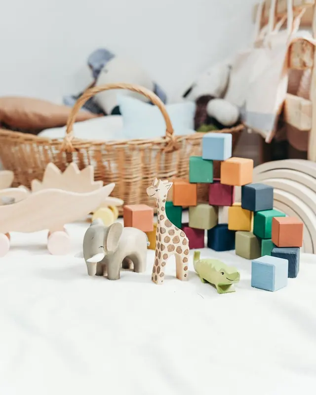 Wooden toys and a wicker basket on a white bed