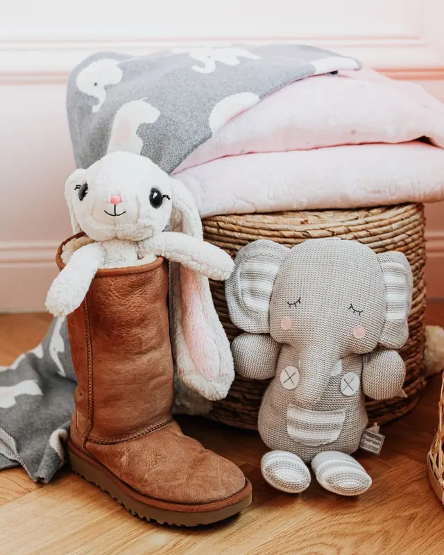 Two plush toys sitting on a wooden floor beside a basket