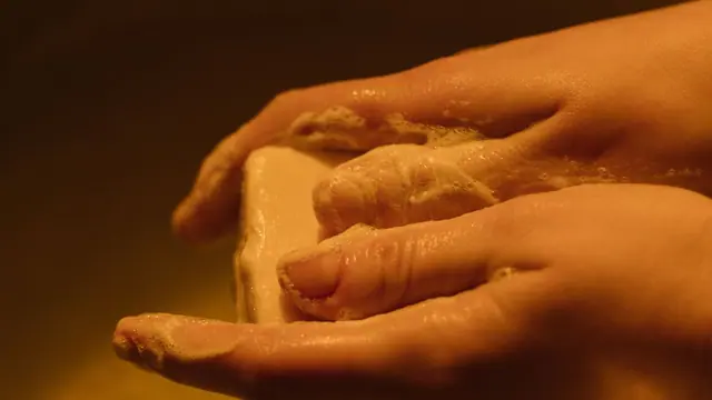 Hands washing a bar of soap in warm light