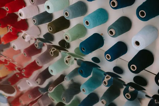 Rows of coloured thread cones on a wall display
