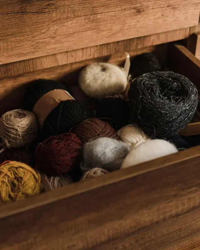 Yarn balls in earthy brown tones in a wooden drawer