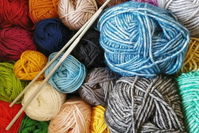 Balls of coloured yarn with wooden crochet hooks laid on top