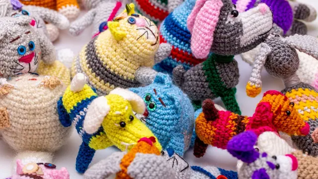 Many small crocheted animals in bright colours on white