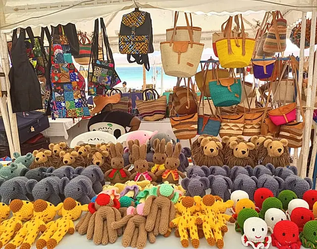 Stall under a white canopy with bags hanging above and rows of crocheted animals below