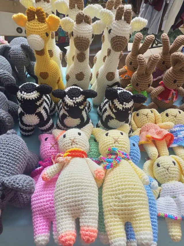 Black and white zebras, giraffes and brown rabbits on one table, with long cats in pink, cream and yellow and small dolls in dresses at the front